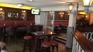 Un interior de restaurante con cabinas, mesas altas y taburetes de bar.