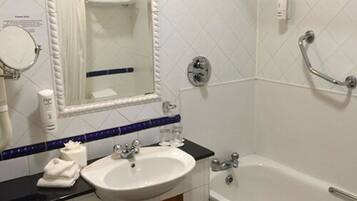 Un baño con lavamanos blanco, espejo, bañera y toallero.