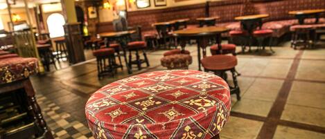 L’intérieur d’un restaurant avec un sol à carreaux, des banquettes rouges recouvertes de tissu et des tables en bois.