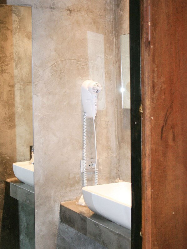 A bathroom with a white sink, a hairdryer mounted on the wall, and a mirror reflecting the sink and hairdryer. - Affittacamere Joss (La Spezia)