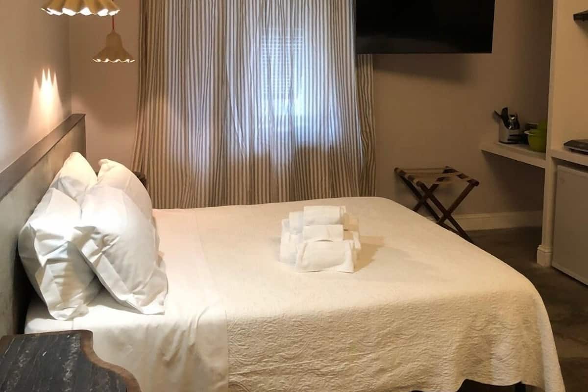Une chambre d’hôtel avec un lit, des oreillers, une télévision, un bureau et une chaise.