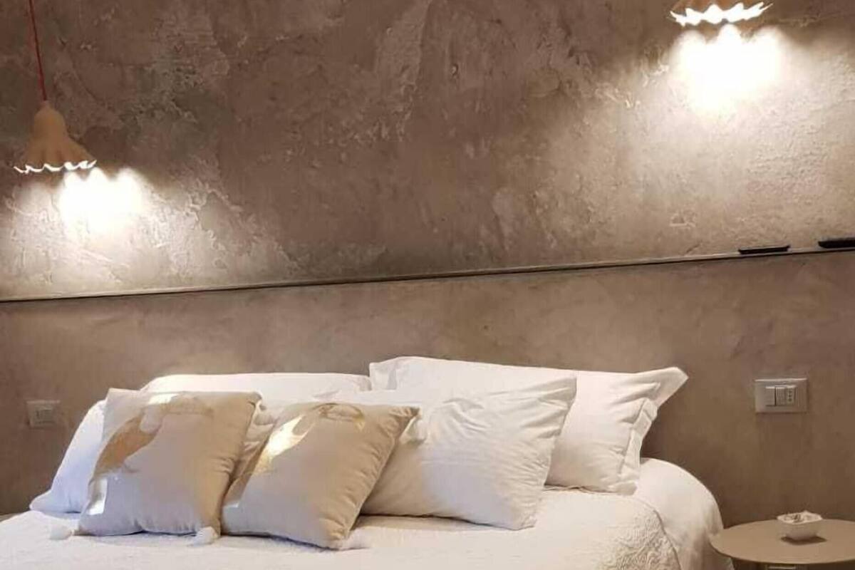Une chambre à coucher avec un lit, des oreillers, une table de chevet et une lampe.