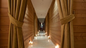 Un pasillo de madera con cortinas atadas en los extremos, suelo pulido y velas a lo largo del camino.