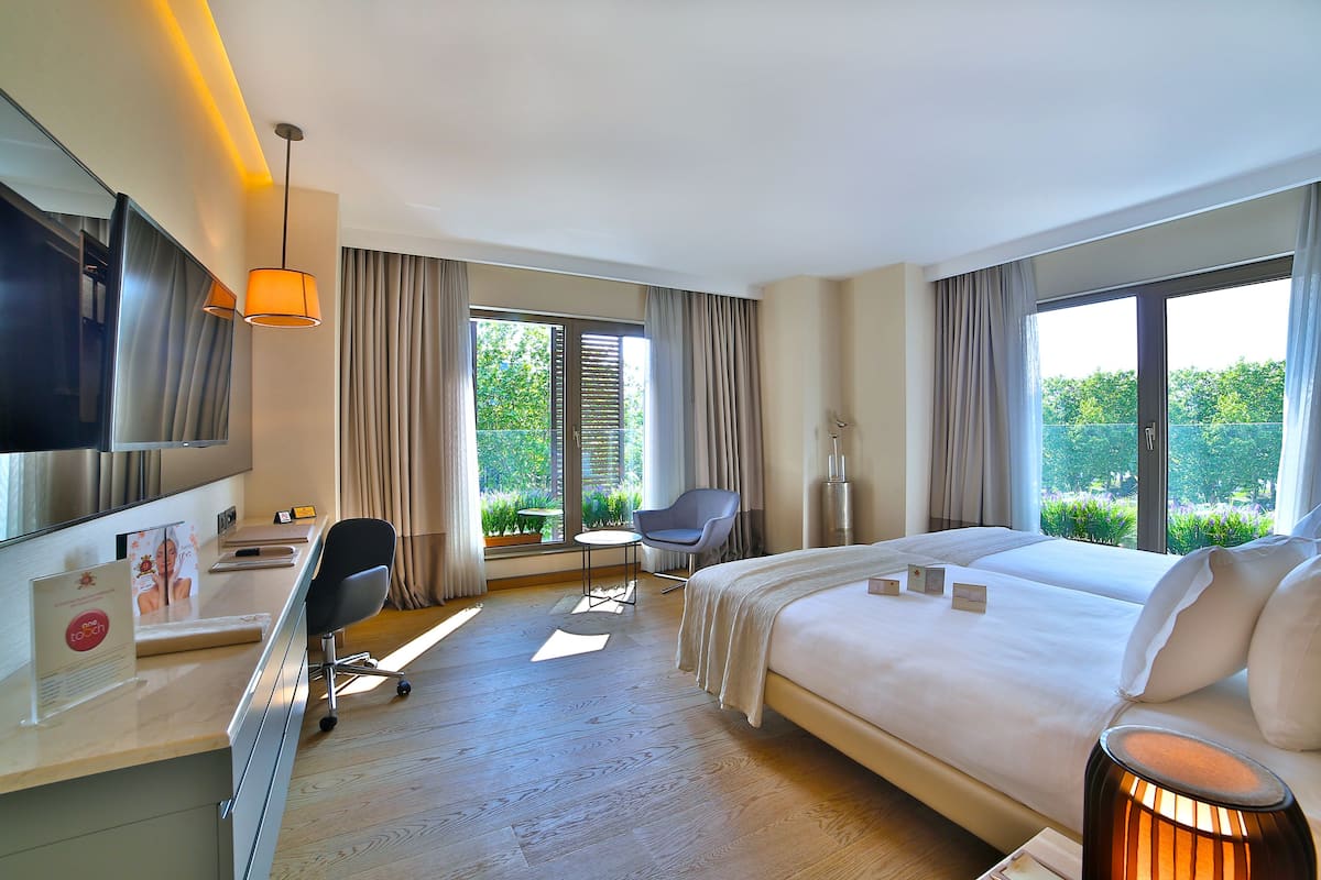 A hotel room with a bed, desk, chair, and a TV.