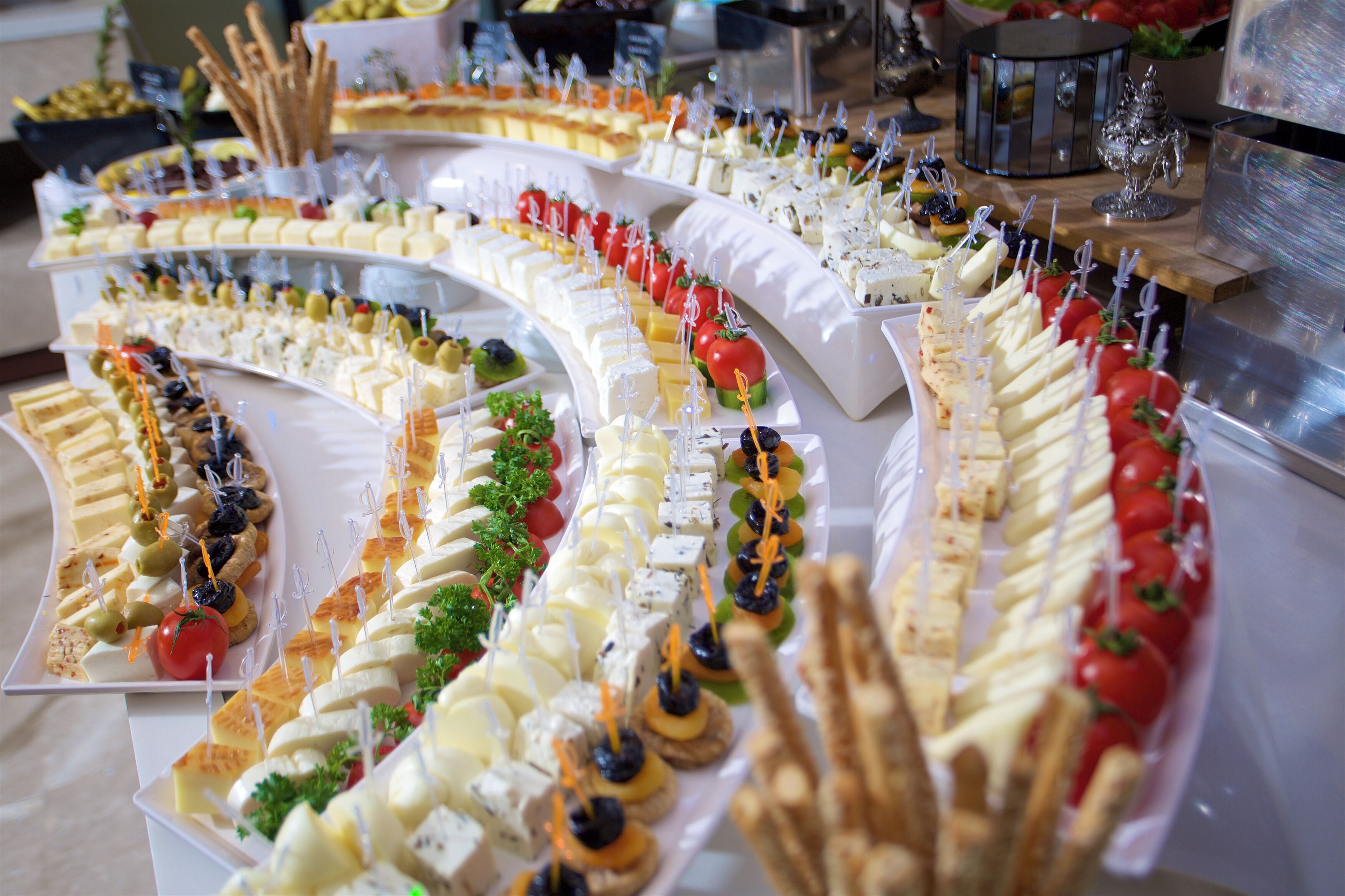 A buffet with various food items arranged on white trays.