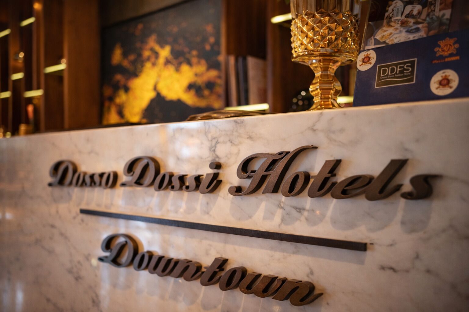 Un mostrador de recepción de mármol con el nombre 'Dassi Hotels Downtown' grabado.
