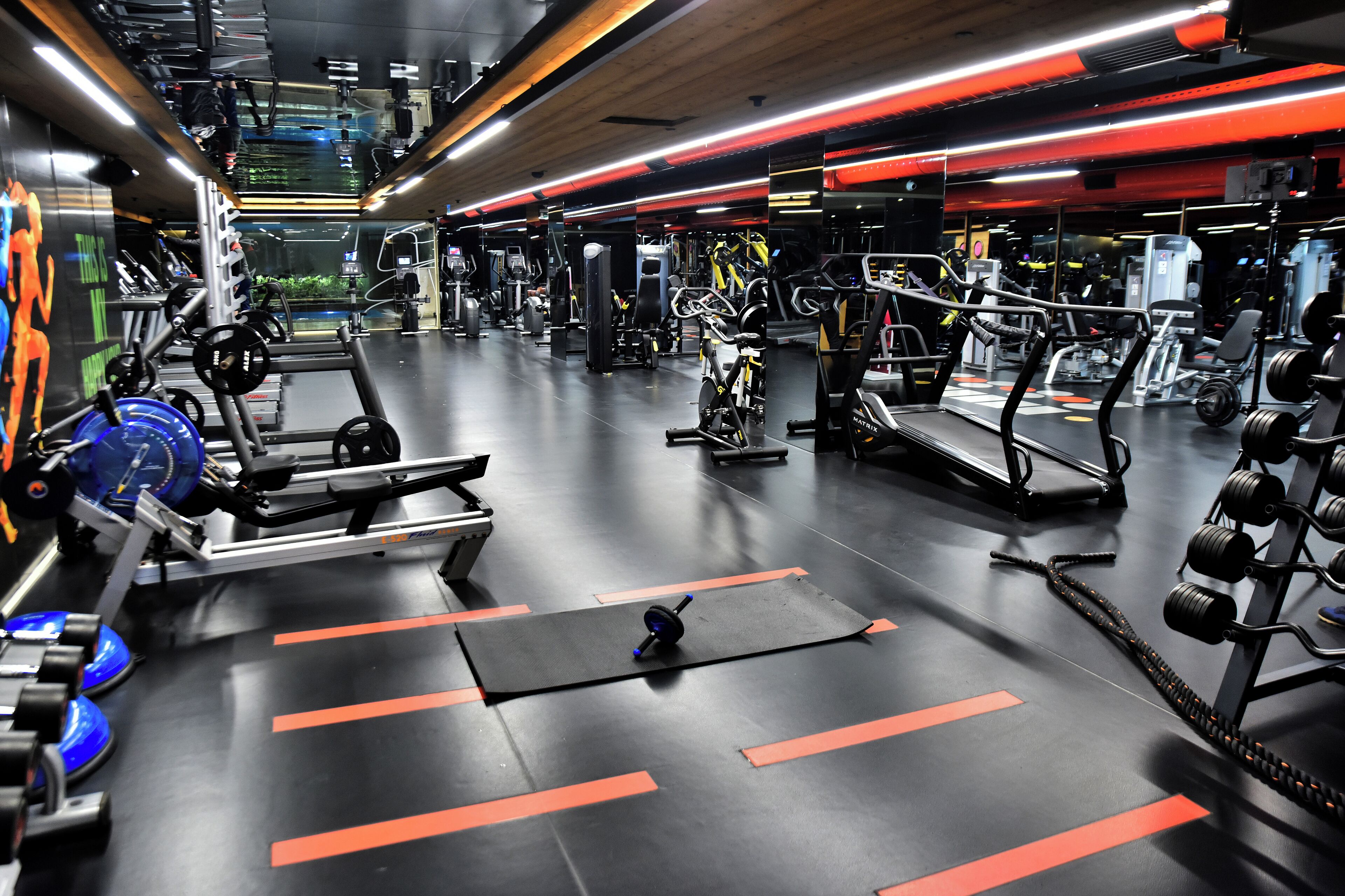 Une salle de sport équipée de divers appareils d’exercice, notamment des tapis de course, des appareils de musculation et des poids libres.