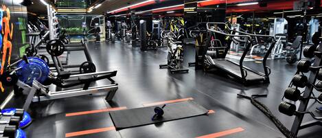 Une salle de sport équipée de divers appareils d’exercice, notamment des tapis de course, des appareils de musculation et des poids libres.