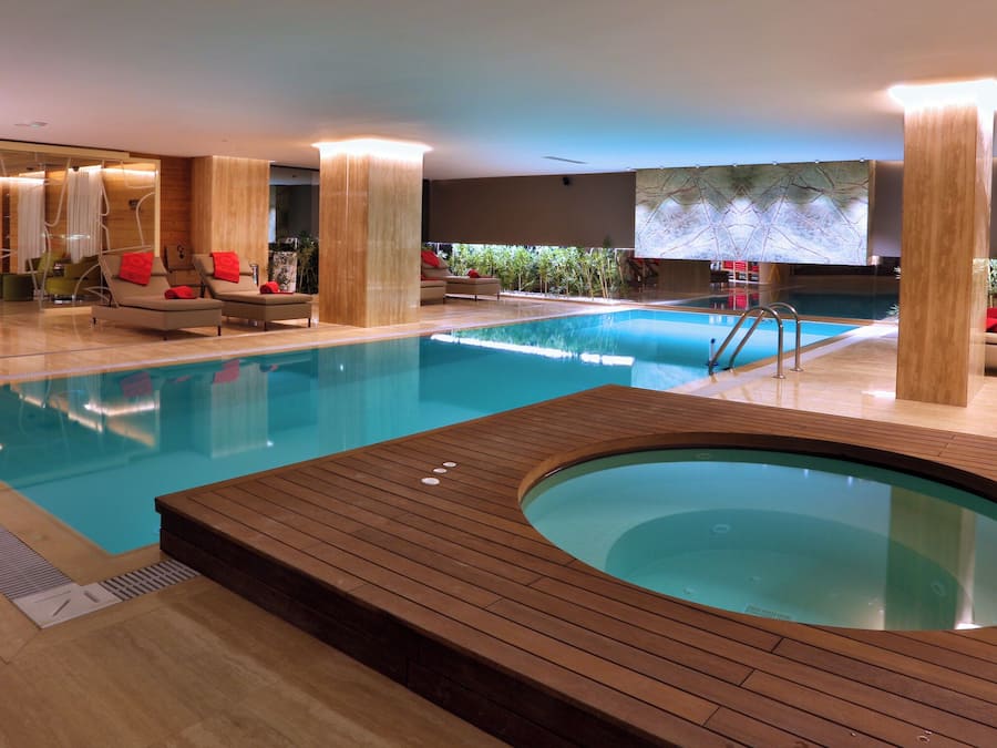 Een binnenzwembad, ligstoelen bij het zwembad, badmeesters op locatie