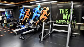 Uma academia com equipamentos de ginástica, uma máquina de remo e halteres.