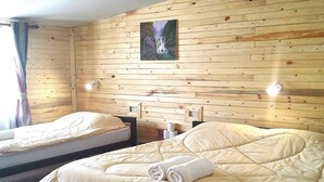 Une chambre avec deux lits, des murs en bois, un tableau et un luminaire au plafond.