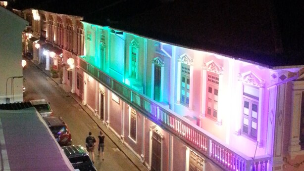 Une rue bordée d’immeubles illuminés par des lumières colorées.