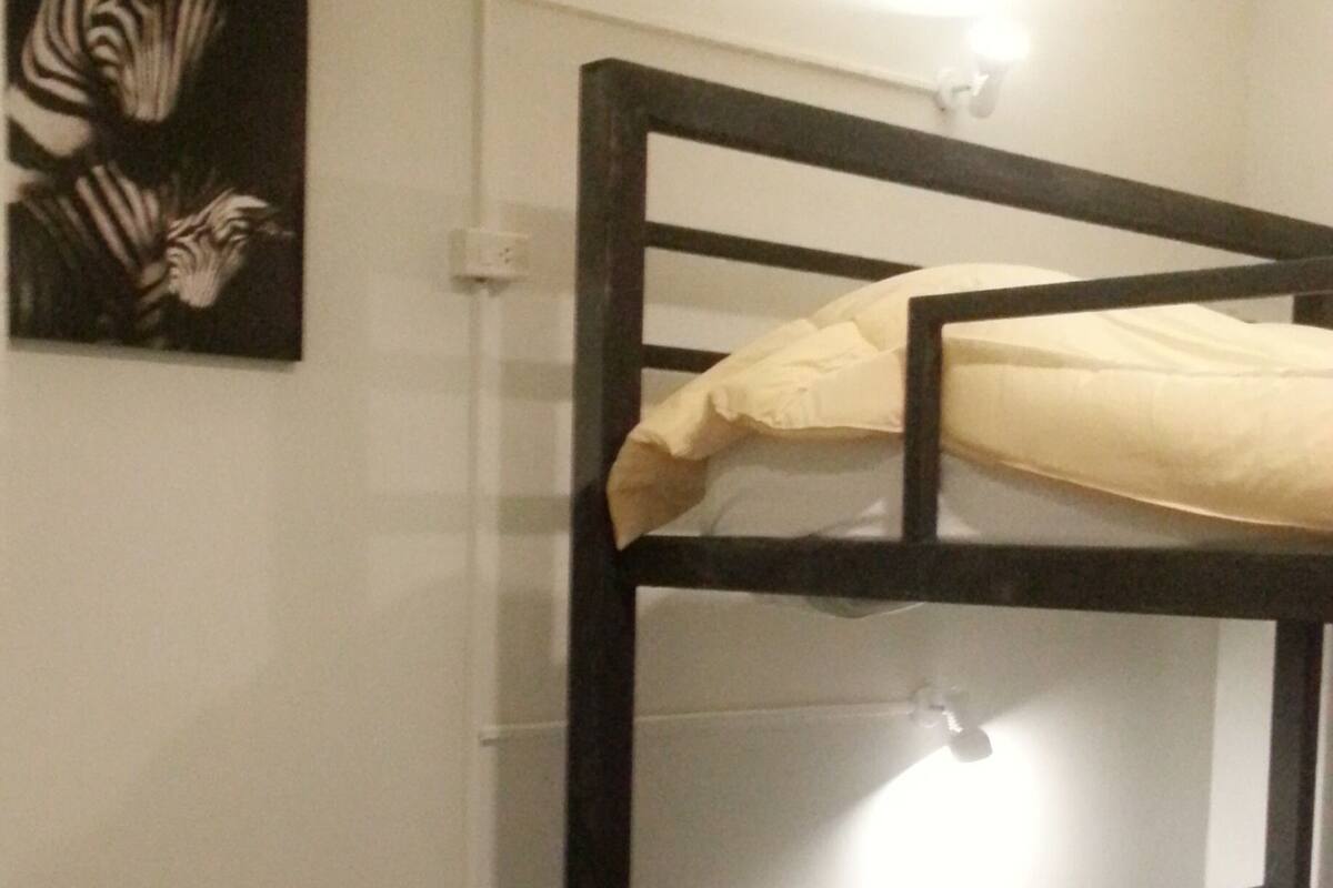 Een slaapkamer met een stapelbed, een klein houten tafeltje en een stoel.