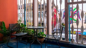 Un balcon avec deux chaises en métal et une petite table ronde, entouré de plantes en pot.