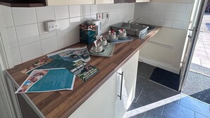 A modern kitchen with white cabinets, a wooden countertop, and a tiled backsplash. - The Minworth Club & Lodge  (Sutton Coldfield)