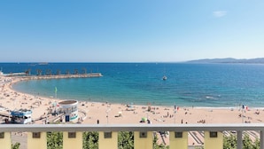 Una playa con un muelle, una torre de socorristas y un cielo azul despejado.