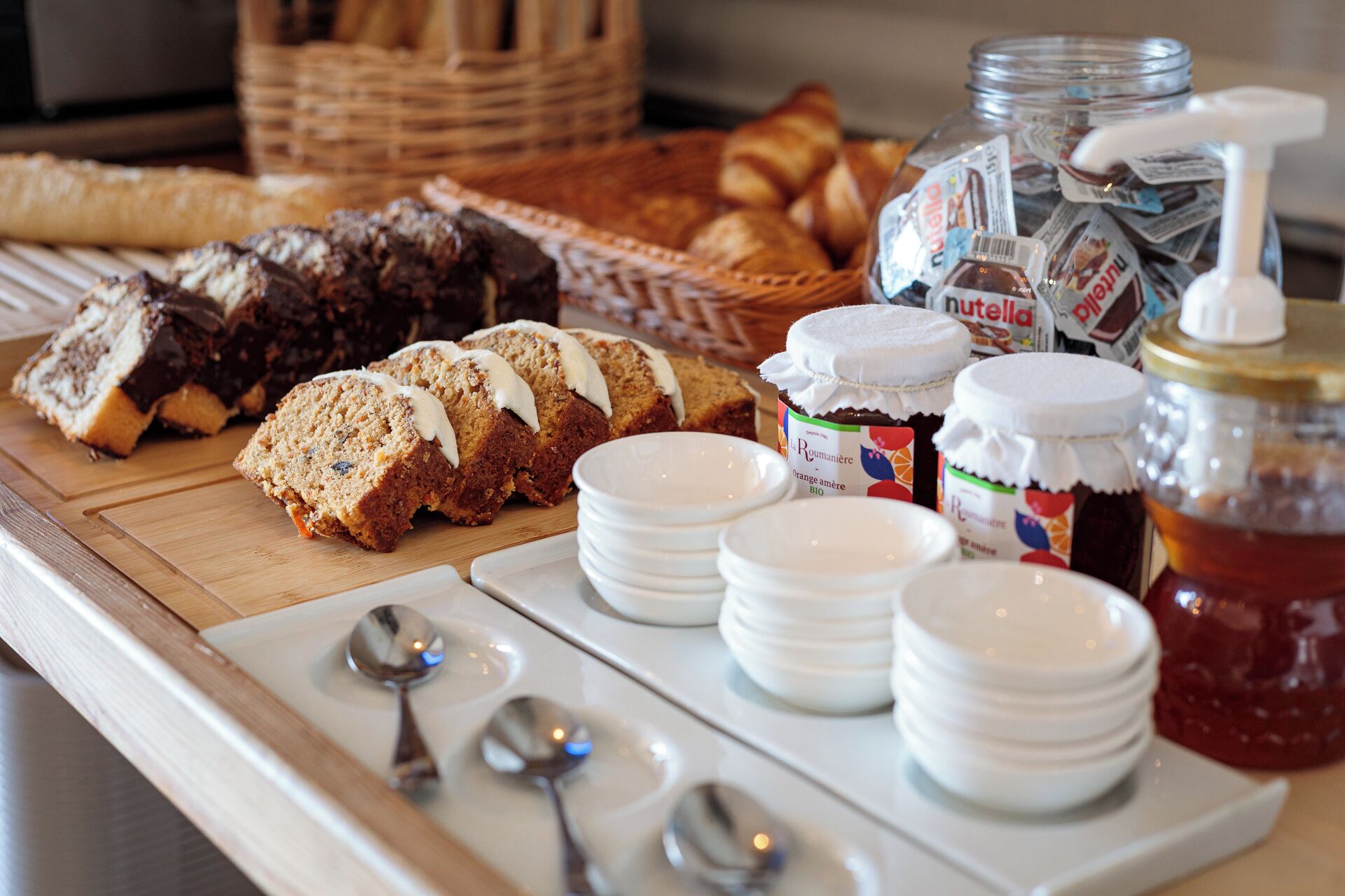 A breakfast buffet with various pastries, jams, and spreads.