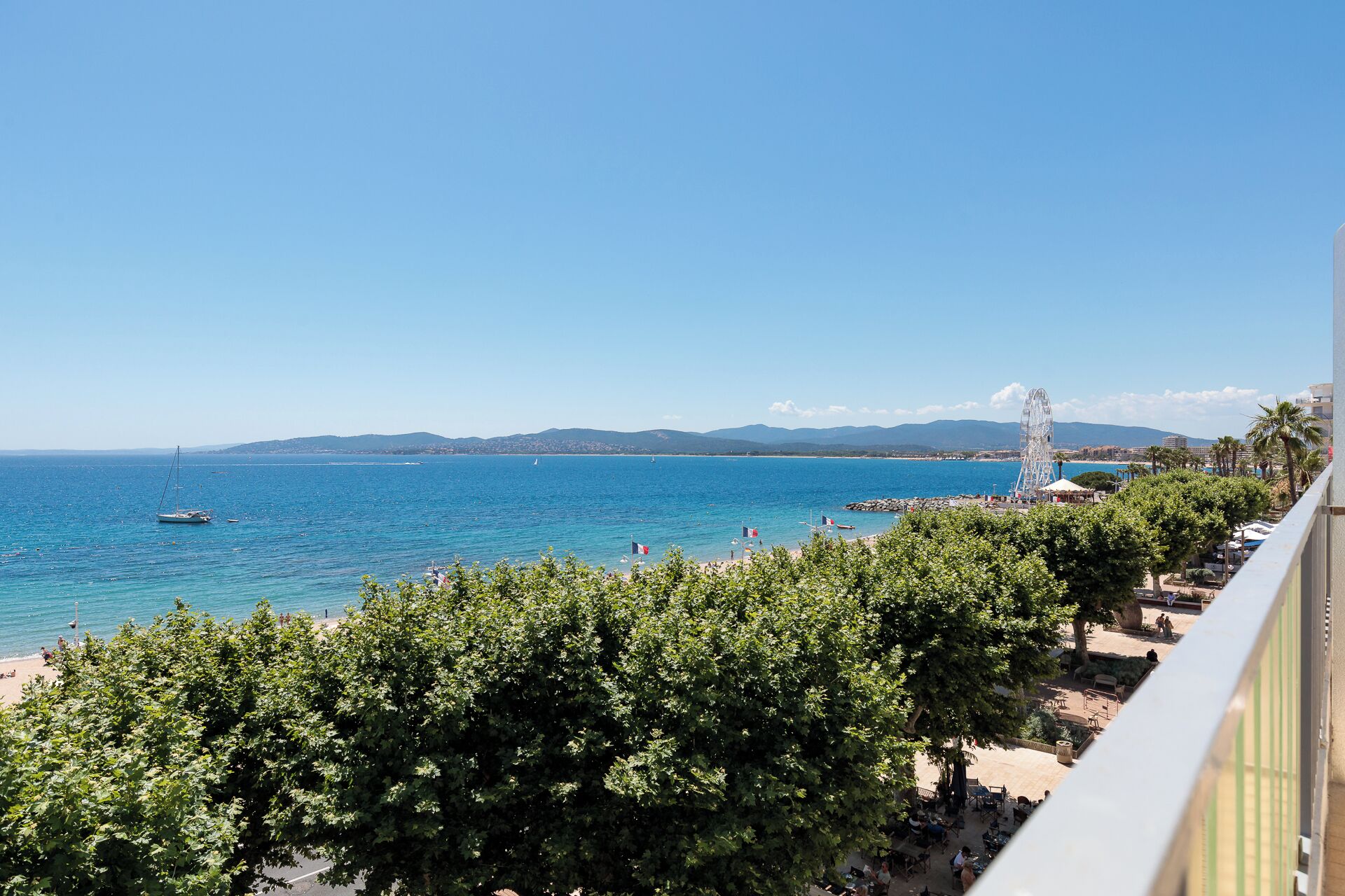 A coastal view with a clear sky, a beach, and a Ferris wheel.