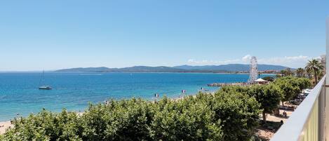 A coastal view with a clear sky, a beach, and a Ferris wheel.