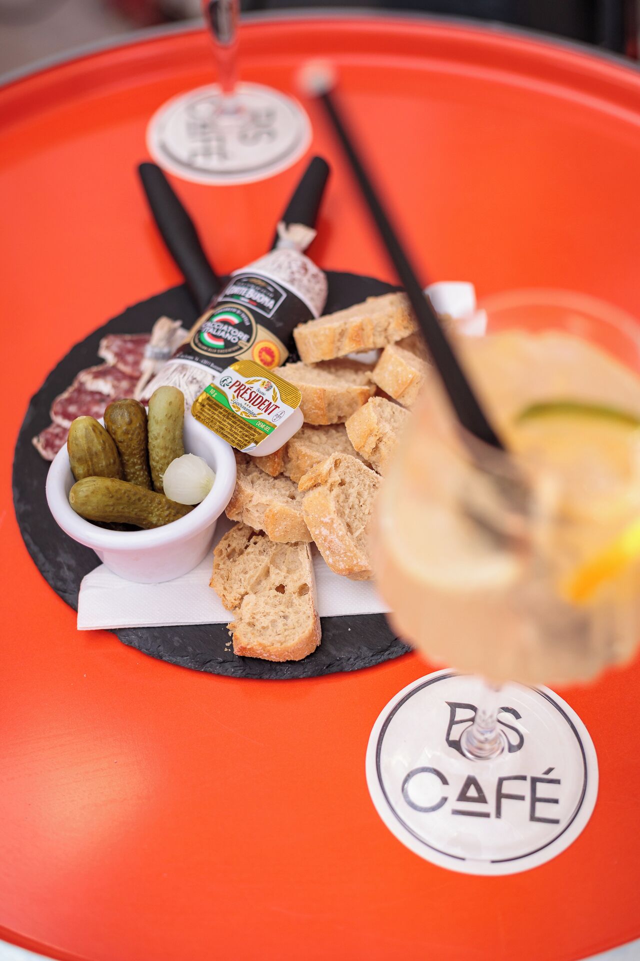 A tray with a bottle of wine, a small bowl of olives, and pieces of bread.