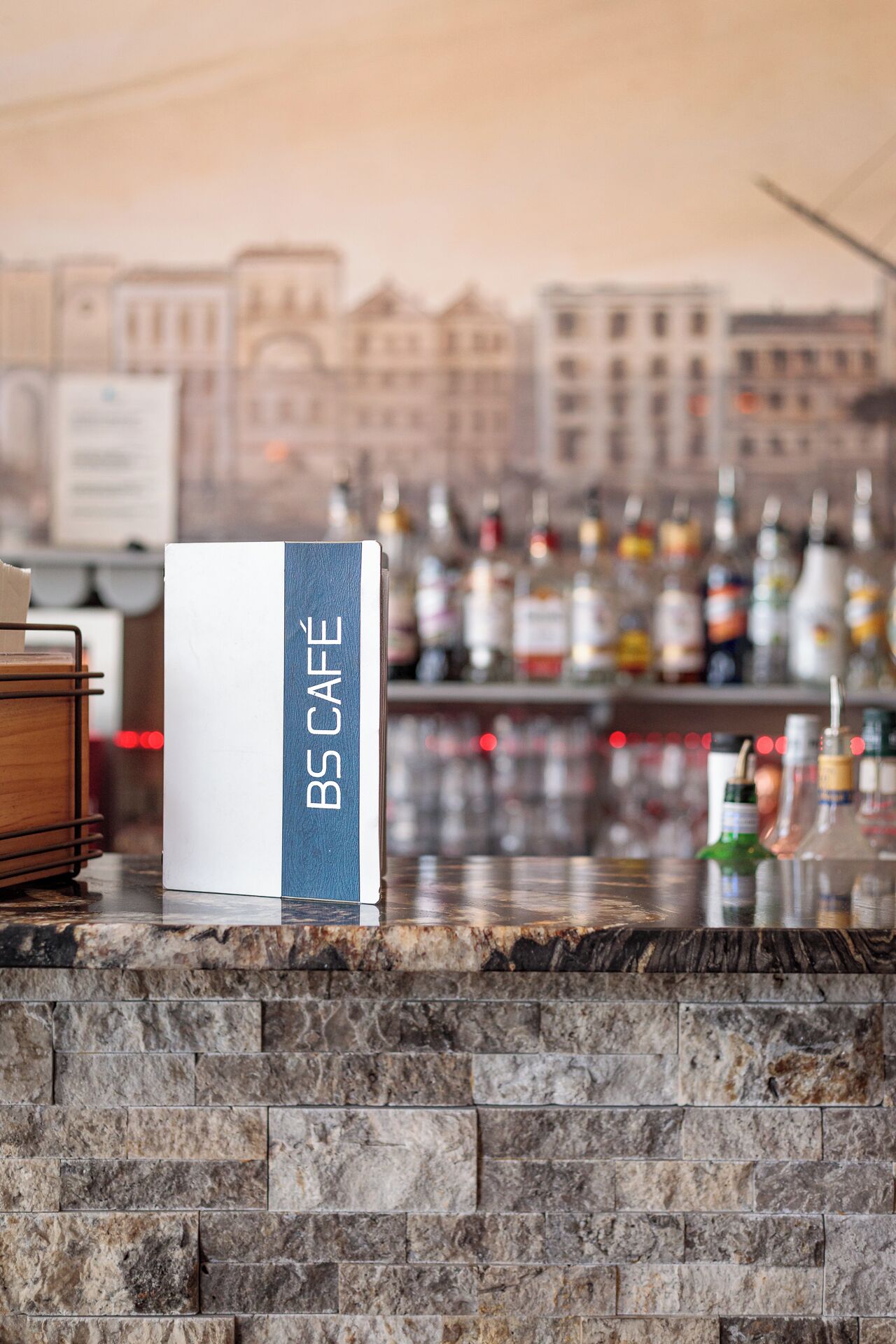 Un área de bar con un letrero que dice 'B5 CAFE' y un paisaje urbano al fondo.