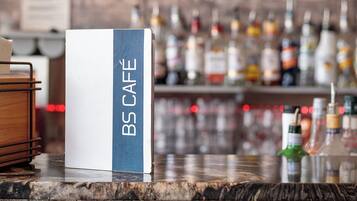 Un área de bar con un letrero que dice 'B5 CAFE' y un paisaje urbano al fondo.