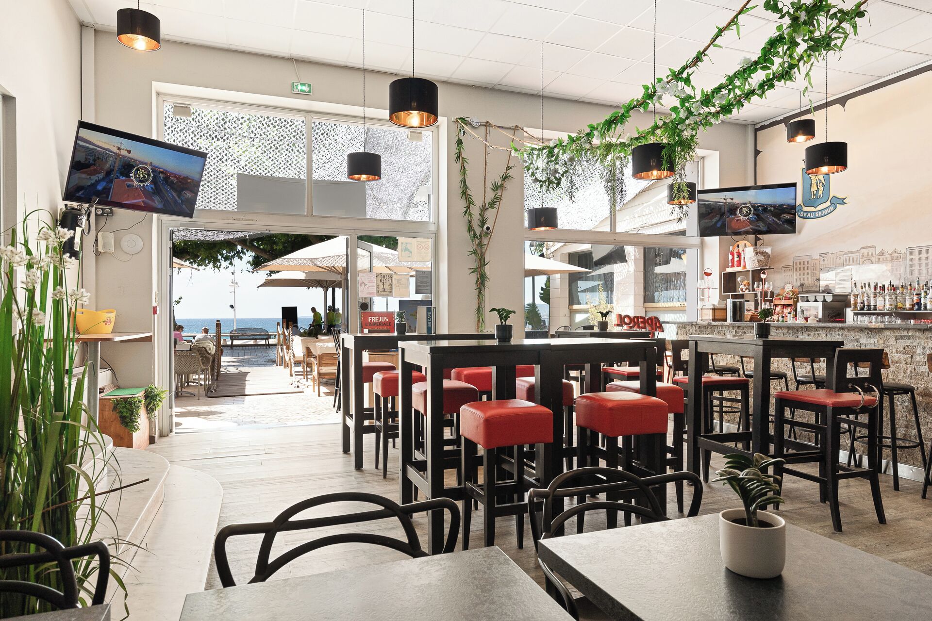 An indoor dining area with tables and chairs, a bar counter, and hanging plants.