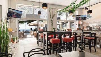 An indoor dining area with tables and chairs, a bar counter, and hanging plants.