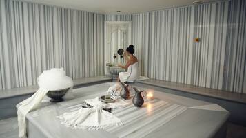 Relax in a serene spa room with a minimalist design, featuring a large mirror and a stylish striped wall.
