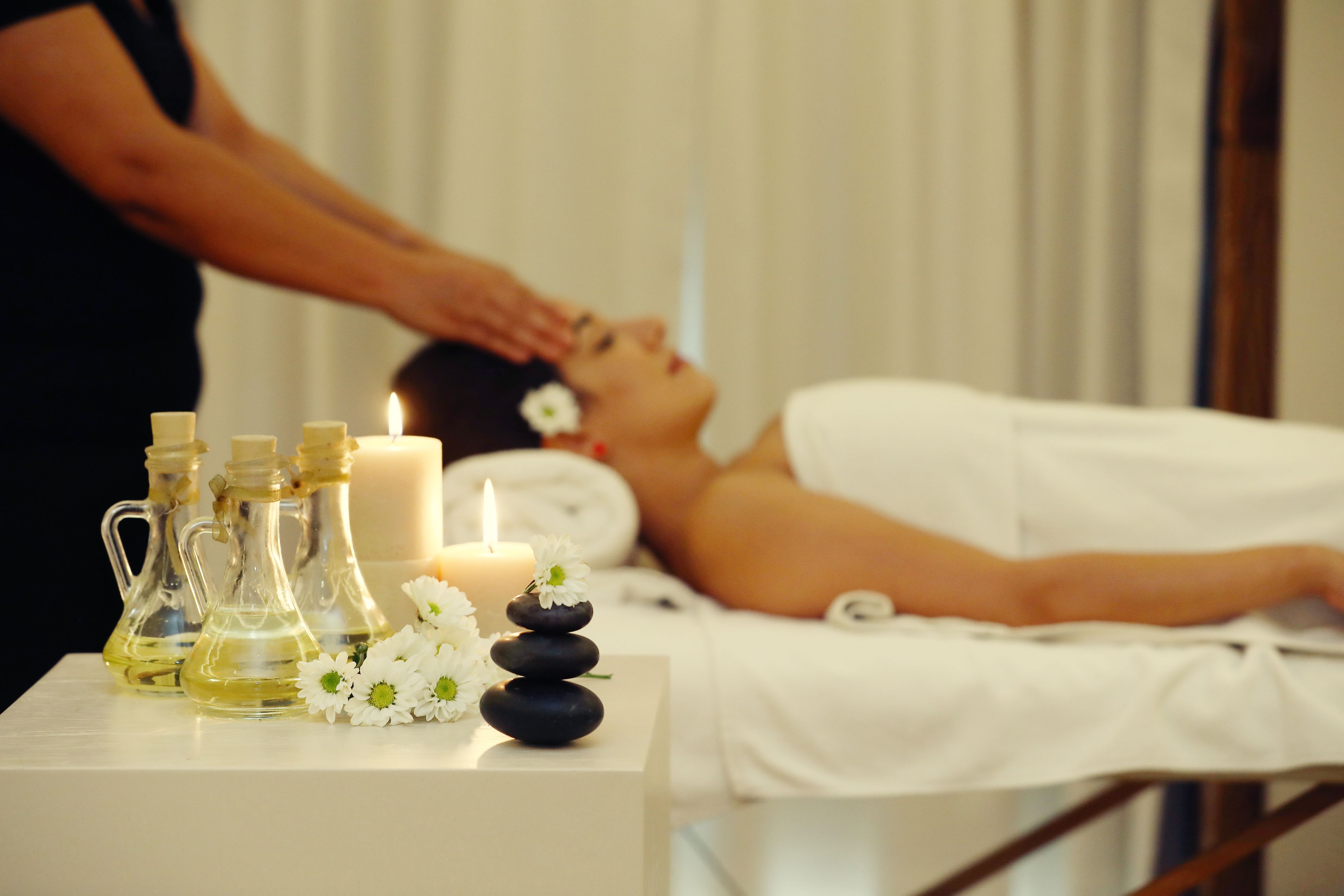 A spa treatment room with a massage table, candles, and essential oil bottles.