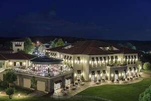 Um edifício grande, com vários andares, um pátio, área de estar externa e um restaurante.