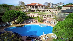 A large swimming pool surrounded by lounge chairs and umbrellas, with a building in the background. - Kemer Country Hotel (Eyup)