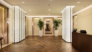 A hotel lobby with a herringbone wood floor, a reception desk, potted plants, and a staircase leading to the upper floors. - Kemer Country Hotel (Eyup)