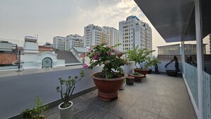 A rooftop terrace with potted plants and a view of high-rise buildings.