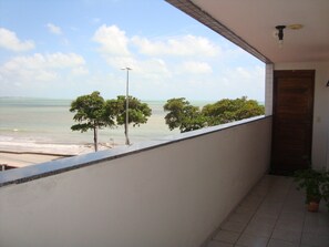 A balcony with a view of the sea and trees.