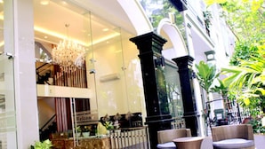 A modern hotel lobby with a glass entrance, a chandelier, and outdoor seating with potted plants. - Song Hung Hotel & Serviced Apartments (Ho Chi Minh City)