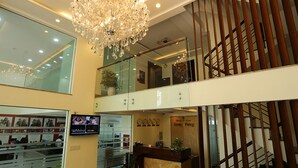 A hotel lobby with a chandelier, a reception desk, a staircase, and a wall with framed pictures. - Song Hung Hotel & Serviced Apartments (Ho Chi Minh City)