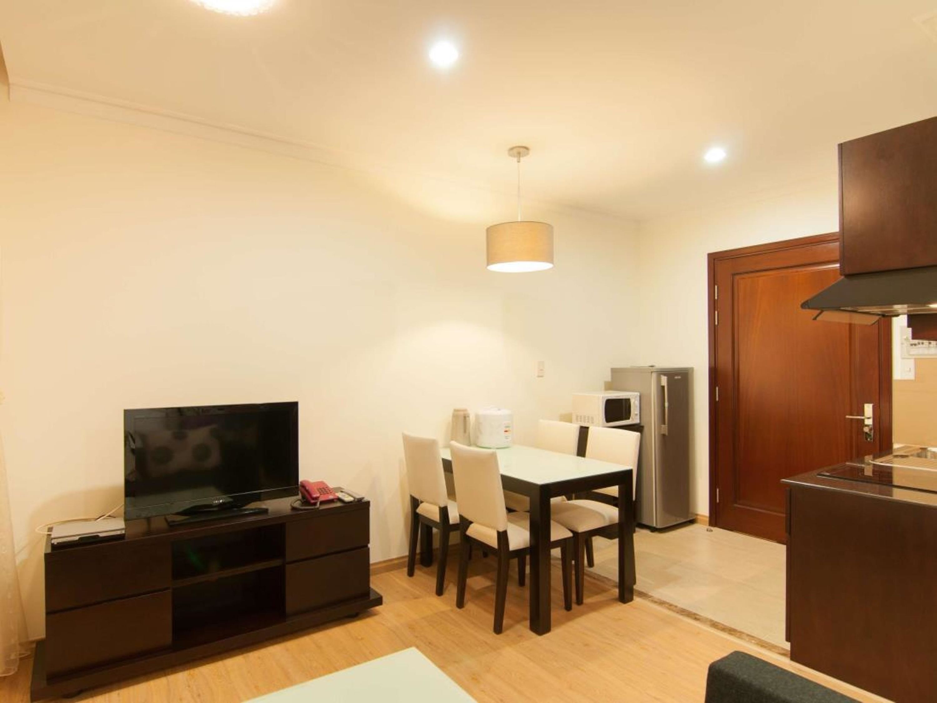 Een compacte leefruimte met een eethoek, kitchenette en een televisie op een donker houten kast.