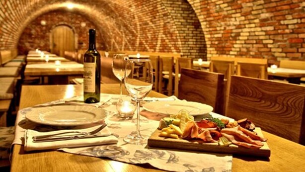 A restaurant with a brick interior and a table set with plates, a bottle of wine, and a glass. - Jades Hotel (Abuja)