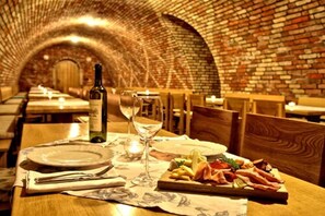 Un restaurante con paredes de ladrillo y una mesa dispuesta con platos, una botella de vino y una copa.