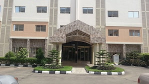 A multi-story building with a central entrance, flanked by columns and a patterned facade. - Jades Hotel (Abuja)