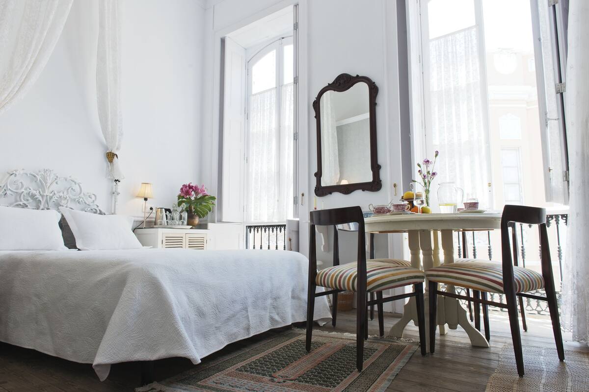Une chambre à coucher avec un lit, une chaise, une table et un miroir.