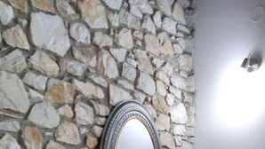 Una pared de piedra con un espejo y una repisa.