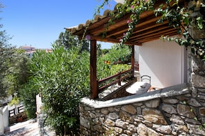 Eine Steinsäule mit einer Holzpergola und einem kleinen Tisch mit Stühlen.