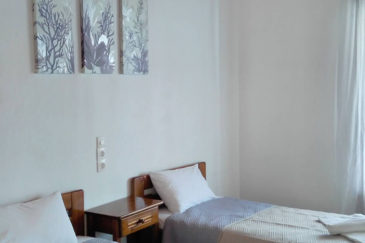 A room with two beds, wooden ceiling beams, and wall-mounted artwork.