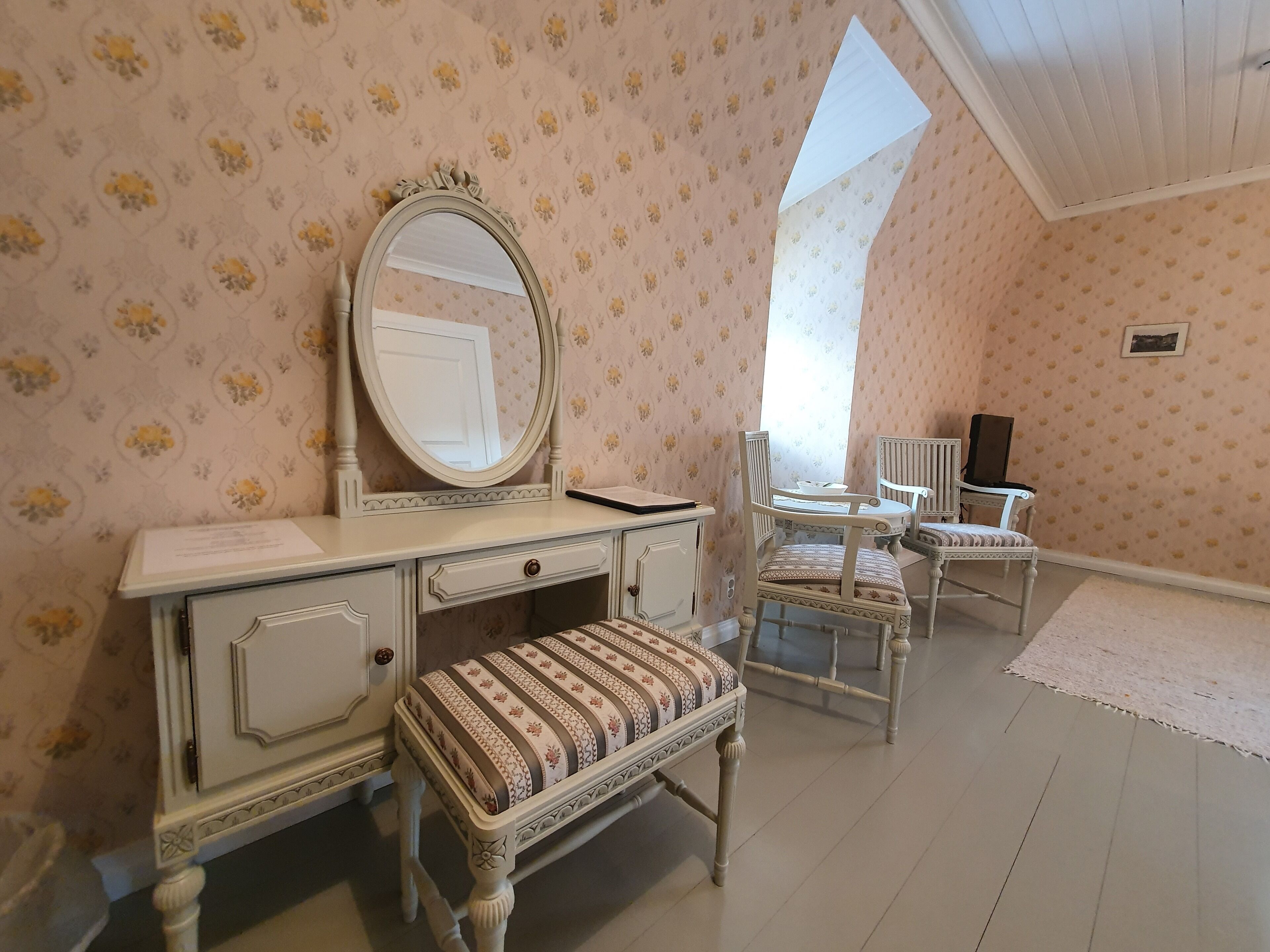 A room with a vanity, a mirror, a bench, and a chair.