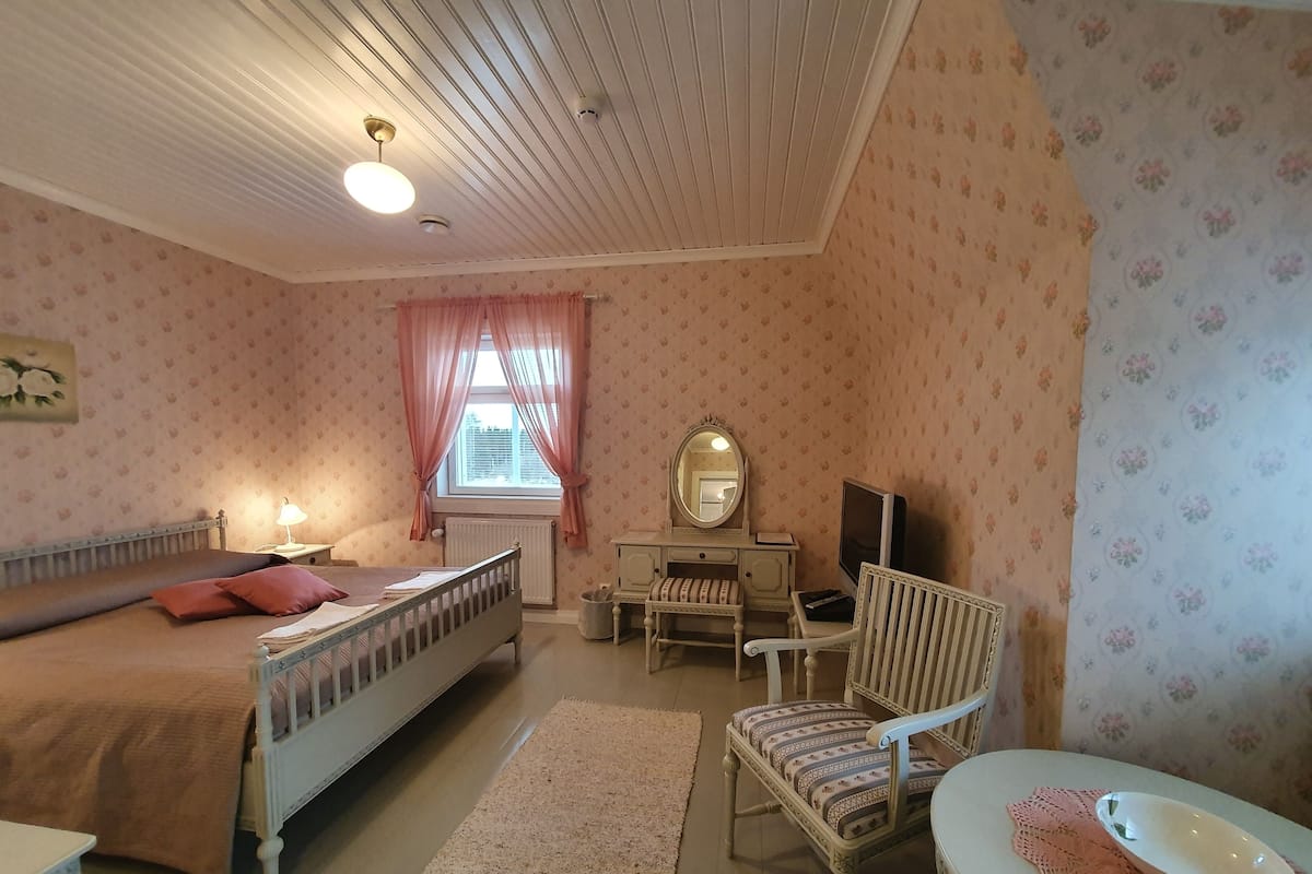 Ein Schlafzimmer mit Bett, Kommode, Stuhl und einem kleinen Tisch mit einer Schüssel.