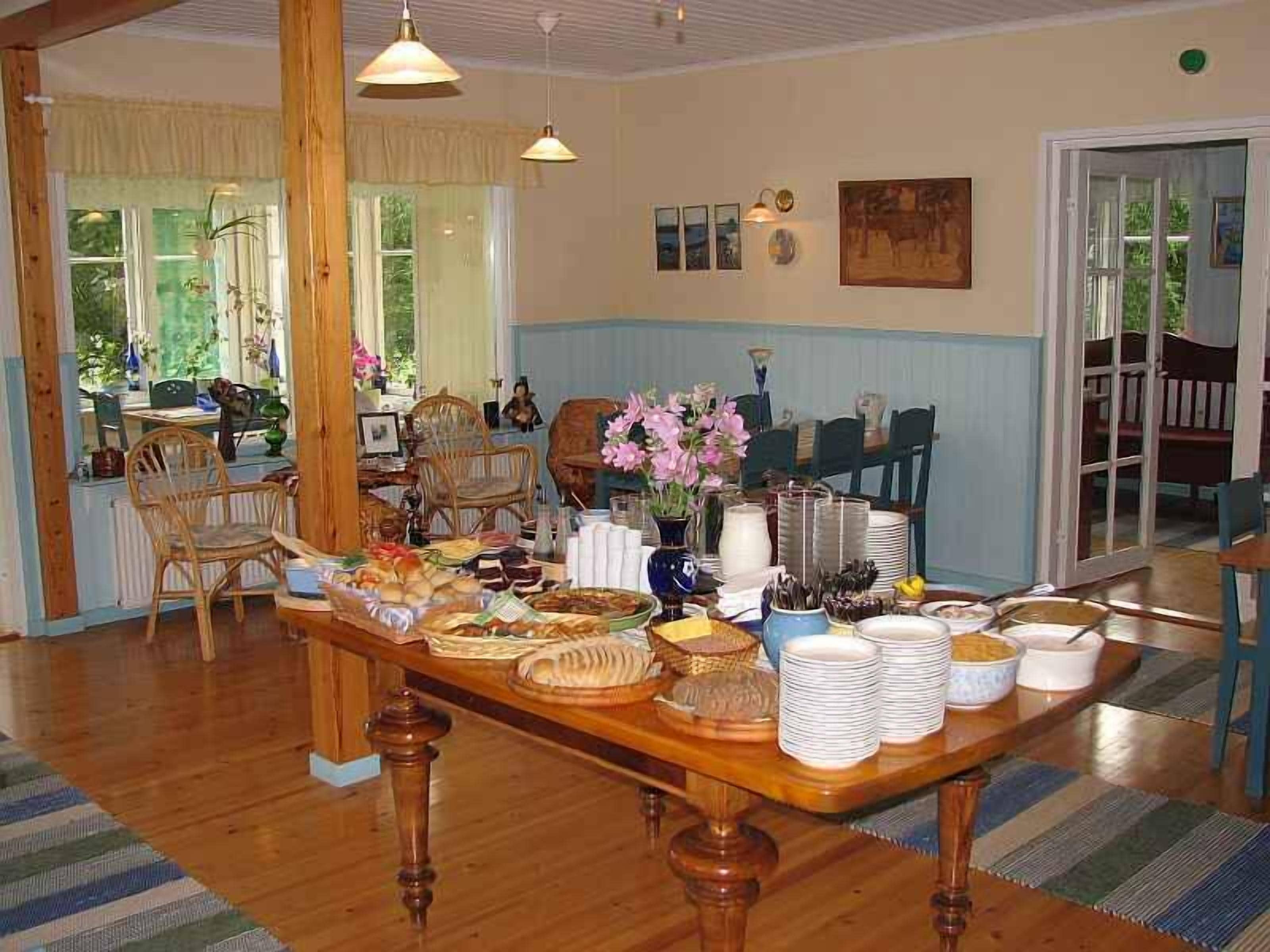 Een eetruimte met een houten tafel, gedekt voor een maaltijd, omringd door stoelen.
