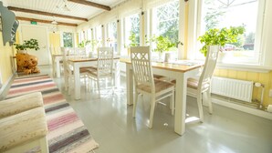 A bright, well-lit room with a wooden table and chairs, large windows, and a striped rug.