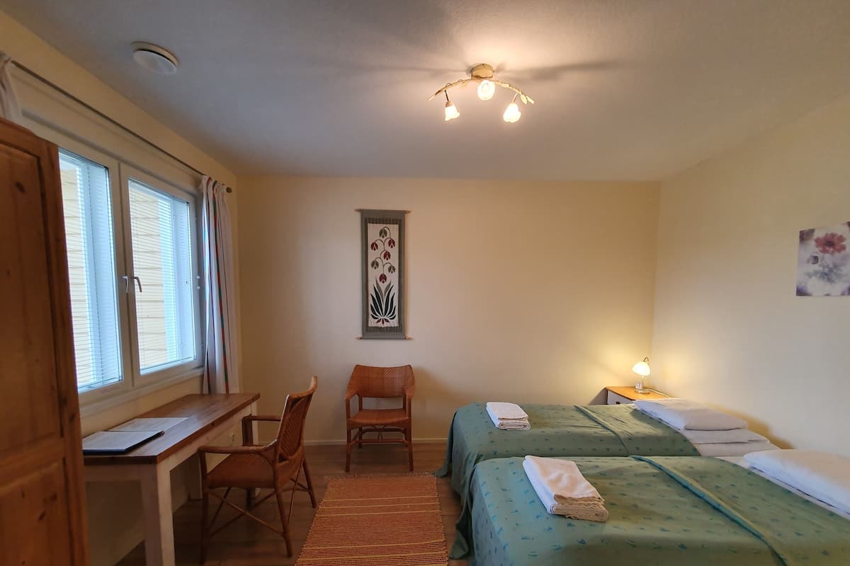 Ein Zimmer mit zwei Betten, einem Schreibtisch und einem Stuhl.
